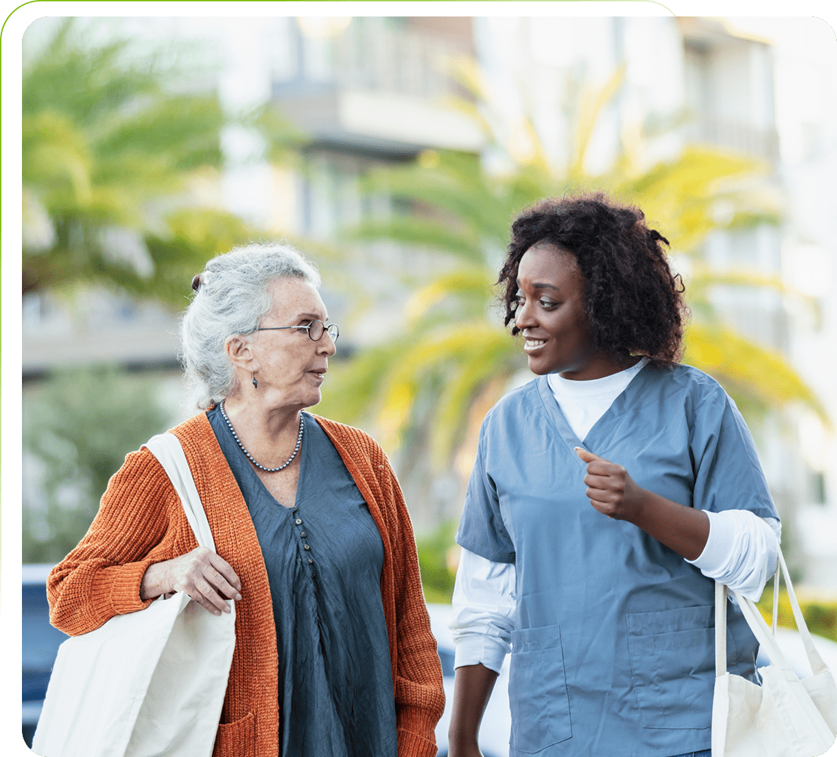 Elderly woman and caregiver walking outdoors together.